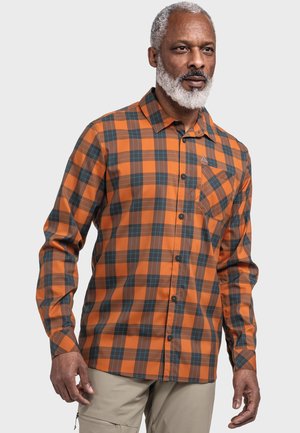 Oranges karierter Button-Up-Hemd mit dunklen blauen und braunen Akzenten, langen Ärmeln und einer Brusttasche, getragen von einem Model.