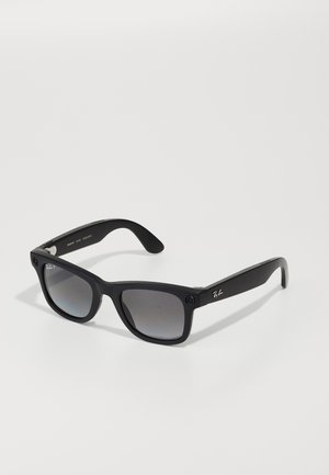 Gafas de sol de plástico negro con lentes oscuros en degradado. Presentan una ligera forma cuadrada y un logo plateado en la patilla. Los brazos texturizados añaden agarre.