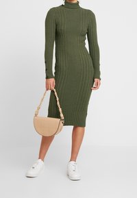 Puuvillane espadrillkleit oliiviroheline ja tekstuurse kaabli mustriga; koos beeži krokodillimustriga koti ja valgete jooksukingadega.