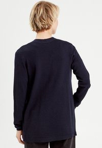 Suéter de manga larga en azul marino oscuro con punto texturizado, cuello redondo y puños y dobladillo acanalados; diseñado para un ajuste relajado.