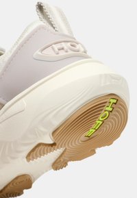 Baskets rose clair avec semelle en caoutchouc texturée. Comprend une semelle intermédiaire blanche, un marquage prononcé et un logo vert néon contrastant sur le talon.