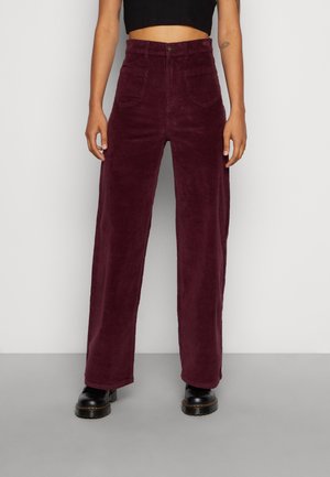 Pantalon en velours côtelé bordeaux à taille haute, jambes droites et poches avant. Doté d'une fermeture à bouton et d'un tissu doux et texturé.