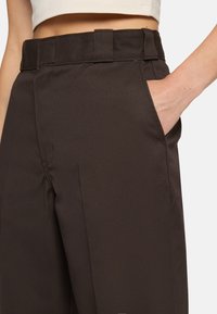 Bruna byxor med en jämn textur, med rak skärning, sidofickor och ett robust midjeband för en säker passform.