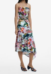 Robe sans bretelles à fleurs mettant en valeur des couleurs vives, des détails plissés, un ourlet asymétrique et un design à superpositions. Assortie avec des sandales navy.