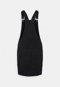 Musta farkkuhaalari-mekko, jossa on säädettävät hihnat, etureisi ja sivutaskut. Hame on polvipituinen ja istuva.