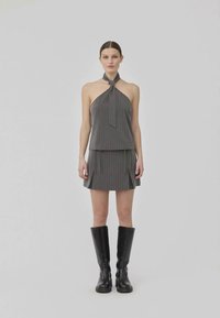 Top halter de rayas grises con detalle de lazo, combinado con una falda a juego con pliegues y botas altas negras hasta la rodilla. Textura suave.