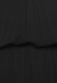 Zwarte stoffen jurk met een gladde textuur, met plooien bij de taille en een vloeiende rok. Eenvoudig, ongecompliceerd ontwerp.