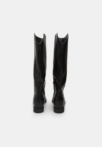 Black leather knee-high boots with a sleek design, pointed upper edges, back zippers, and flat soles. Smooth texture and minimalistic style.