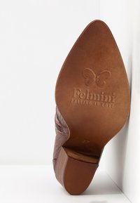 Brun läder klackskor med en texturerad yta, rundad spets och en solid klack som liknar trä, med "Felmini" präglat på sålen.