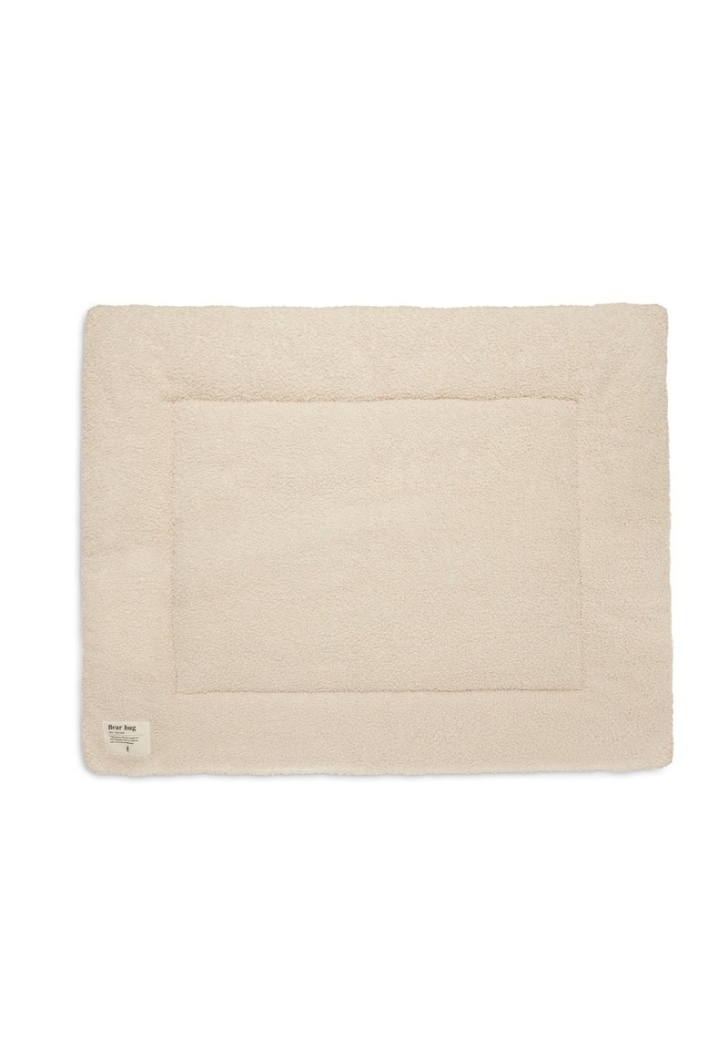 Tapis pour animaux de compagnie rectangulaire de couleur crème avec une surface douce et текстurée et une bordure en coutures. Comprend une petite étiquette dans un coin.