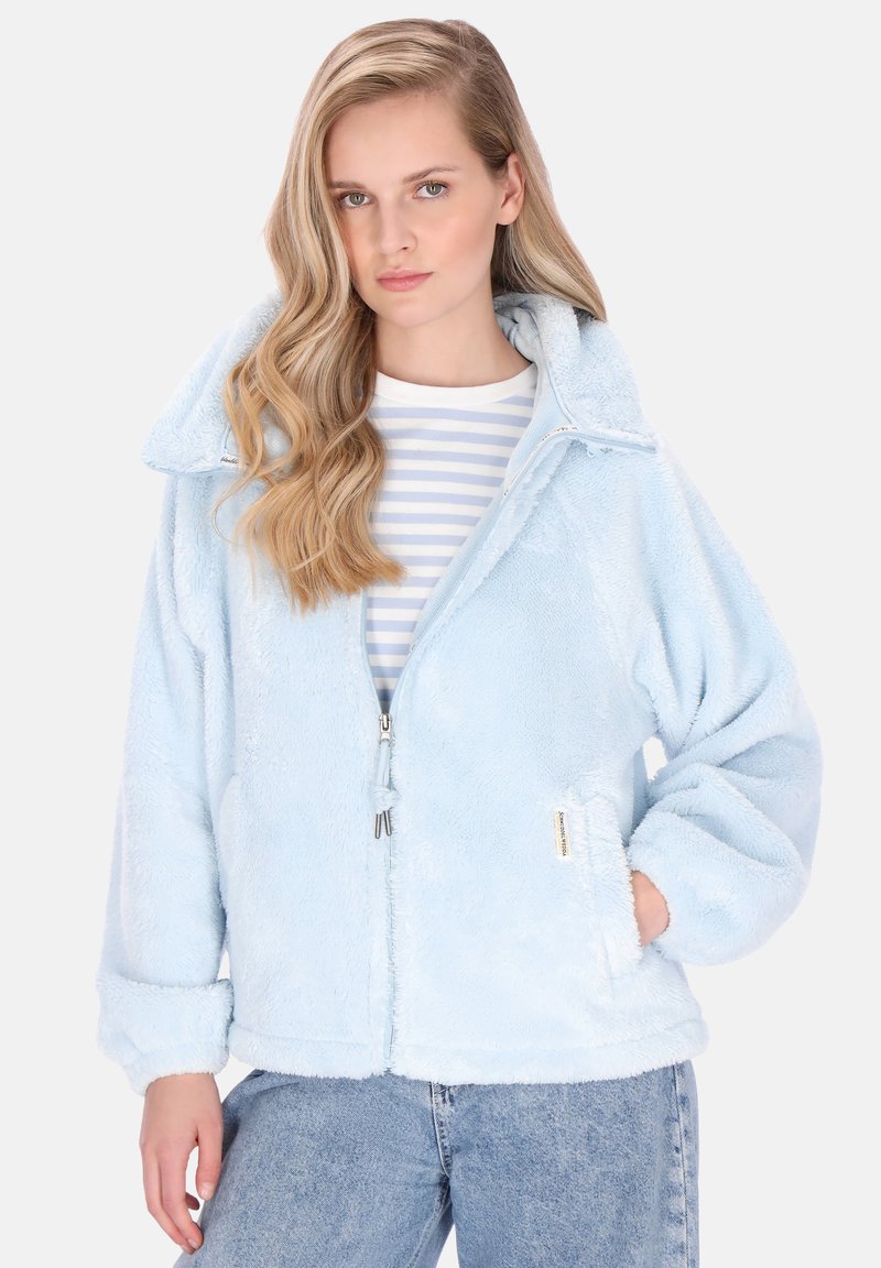 Jachetă din fleece albastru deschis cu fermoar frontal, guler mare și buzunare laterale. Croială supradimensionată cu textură moale, asortată cu un tricou în dungi pe dedesubt.