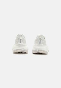 Baskets blanches de sport avec un dessus texturé, une semelle rembourrée et un talon renforcé. Marquage subtil et éléments de design minimalistes.