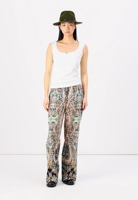 Top blanco sin mangas, pantalones de pierna ancha multicolores con estampados florales y paisley, y un sombrero verde oscuro. Tela suave y ajuste cómodo.
