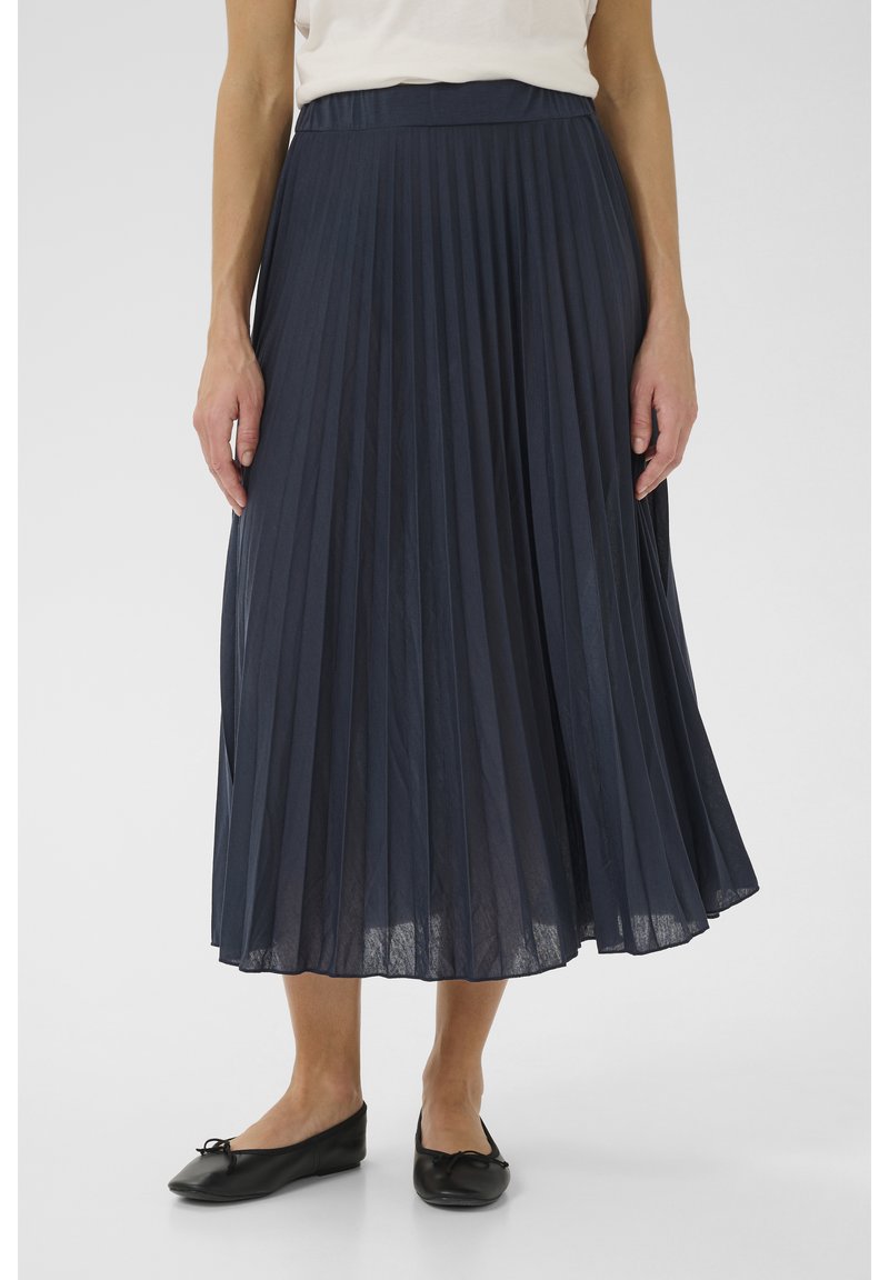 Marinblå plisserad midi-kjol tillverkad av lätt material med en mjuk textur. Matchas med svarta platta skor för en komplett look.