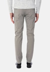 Pantaloni in twill di cotone grigi con una vestibilità dritta e due tasche posteriori. La vita si posiziona appena sopra i fianchi, abbinata a scarpe nere.