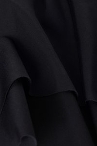 Tissu noir avec une texture lisse et mate, présentant un léger éclat. Le matériau tombe doucement avec des bords nets et pliés.