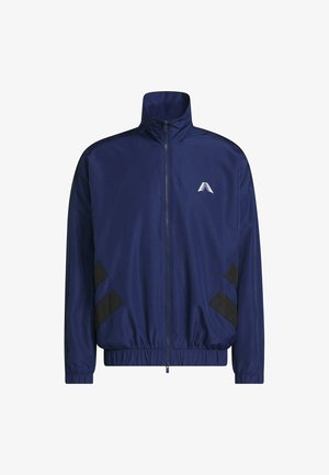 Veste zippée bleu marine avec col montant, poignets et ourlet élastiques, rayures noires diagonales près des poches, et petit logo triangulaire blanc sur la poitrine.