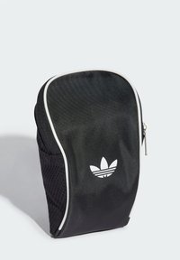 Bolsa atlética de malla negra con un acabado brillante, ribete blanco y un logo impreso de tres rayas en la parte frontal. Cierre con cremallera en la parte superior.