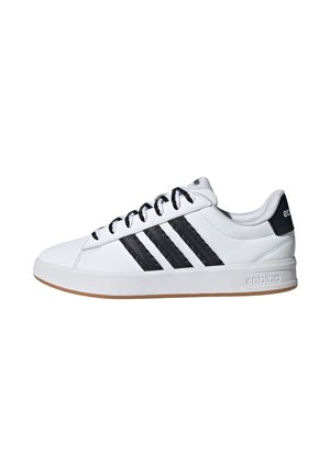 Baskets basses blanches avec des rayures noires, des lacets noirs, une semelle en gomme et un logo adidas sur le talon et le côté de la semelle intermédiaire.