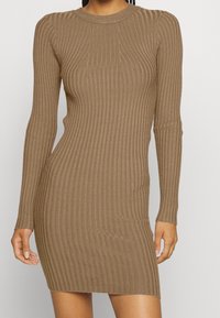 Abito a maglia a coste di colore marrone caldo, con maniche lunghe, scollatura rotonda e silhouette aderente che arriva fino a metà coscia.