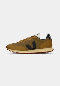 Sneaker in microfibra e rete marrone con accenti neri, punta arrotondata, chiusura con lacci e suola in gomma rossa. Presenta un logo sul tallone.