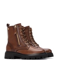 Botas de cuero marrón hasta el tobillo con herrajes dorados, cordones en la parte delantera y cremallera lateral. Suela gruesa de goma negra con un patrón de banda de rodadura resistente.