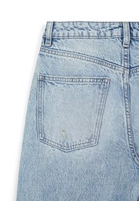 Jeans en denim bleu clair avec une poche à rabat à l'arrière, présentant une texture usée et des coutures contrastantes le long de la poche et de la taille.