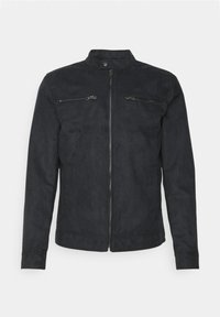 Giacca in suede nero con colletto alto, chiusura con zip e due tasche sul petto con zip. Tessuto liscio con vestibilità sartoriale e maniche lunghe.