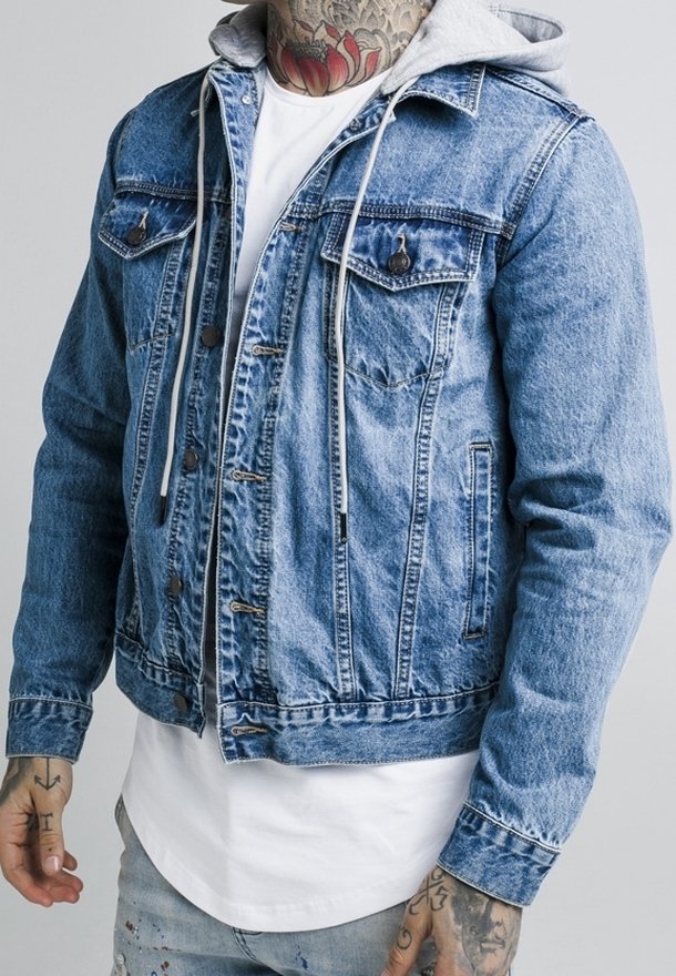 Jeansjacka i ljusblått med klassisk snitt, två bröstfickor, bruna knappar och en grå hoodie under.