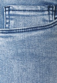 Denim kankaan vaaleansininen väri, jossa on hieman haalistunut kuvio. Sisältää takataskun, jossa on vahvistetut saumat reunoilla.