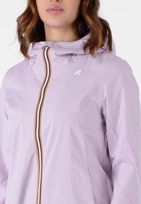 Giacca viola chiaro con cappuccio, caratterizzata da una cerniera verticale a strisce in rosso, giallo e bianco. Include un logo accentuato sul petto.