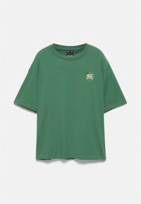 T-shirt vert à manches courtes avec un petit motif tropical et un texte sur la poitrine gauche, présenté à plat sur un fond blanc uni.