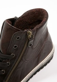 Braune Leder-Stiefelette mit runder Zehenpartie, Schnürverschluss, Reißverschluss und einem weichen, strukturierten Innenfutter. Verfügt über eine weiße Gummisohle.