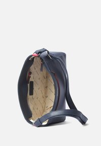 Marineblauwe leren handtas met een gestructureerde vorm. Heeft een gladde buitenkant, een rode ritssluiting, en een beetjesbeige interieur met een schouderriem.