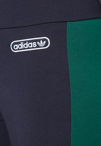 Marina leggings med en grön sidopanel, tillverkade av stretchigt tyg. Utmärkande vit Adidas-logotyp med trefoil på låret.