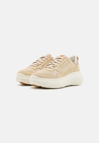 Sneaker beige in suede con design perforato, suola crema e dettagli marrone chiaro. Presenta lacci e collo imbottito per il comfort.