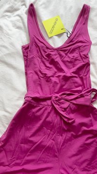 Vestido sem mangas fúcsia com um decote em V profundo, cintura franzida, cinto ajustável e textura de tecido suave. Etiqueta da marca presa.