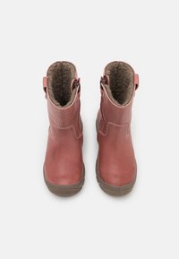 Červené kožené kotníkové boty s měkkou podšívkou, kulatou špičkou a bočním zipem. Gumová podrážka s texturovaným gripem pro stabilitu.