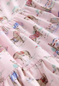 Tissu rose plissé avec de petits chevaux portant des couvertures colorées et de petits détails de traîneaux et de plaques de neige.