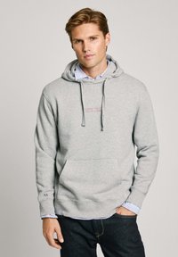 Sudadera gris con capucha y un bolsillo frontal, que presenta un logo de "PEPE JEANS" en rosa. Diseño casual con puños y dobladillo acanalados. Superpuesta con una camisa de cuello.