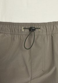 Graue Shorts mit elastischem Bund, ausgestattet mit einem Kordelzugverschluss mit schwarzem Beschlag, strukturiertem Stoff und einer Seitenasche.