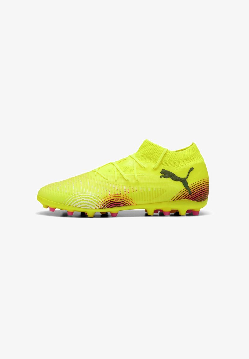 Botín de fútbol amarillo con un cuello tipo calcetín, parte superior texturizada, acentos en degradado rojo y negro, y tacos multicolores para agarre.