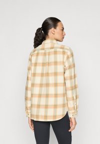 Camicia a quadri in crema con linee arancioni e blu, realizzata in tessuto morbido. Presenta un yoke sul retro e polsini con bottoni, con un orlo curvo.