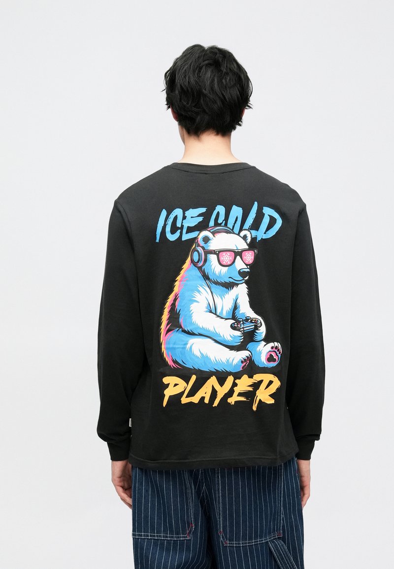 Zwart shirt met lange mouwen met een kleurrijke afbeelding van een ijsbeer die een koptelefoon draagt en een gamecontroller vasthoudt, met de tekst "ICE COLD PLAYER."