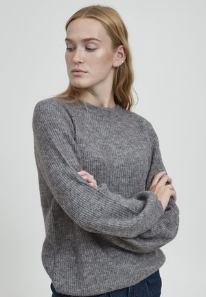 Gray knitted sweater with a crew neck, textured fabric, and slightly puffed long sleeves, paired with dark blue jeans.