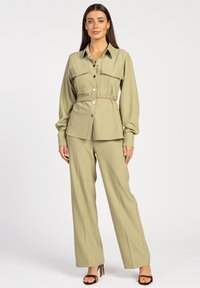 Olive green, long-sleeve belted shirt with two front pockets and button closure, paired with matching wide-leg trousers and heeled sandals.