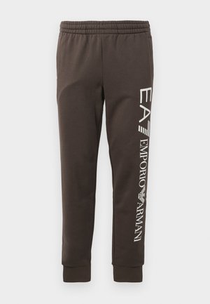 Braune Sweatpants mit einem elastischen Bund, schmal zulaufenden Beinen und weißem Logo-Text "EA7 Emporio Armani", der entlang der Seite aufgedruckt ist.