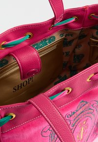 Borsa a tracolla in pelle rosa con hardware dorato, cordini blu e un interno a motivo con testo stampato e accenti di design.