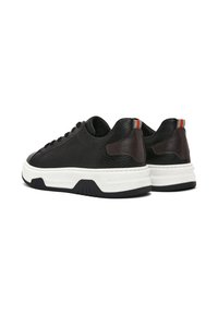 Sneaker in pelle nera con finitura testurizzata, soletta bianca e suola in gomma scura. Presenta dettagli in pelle marrone e una striscia colorata sul tallone.