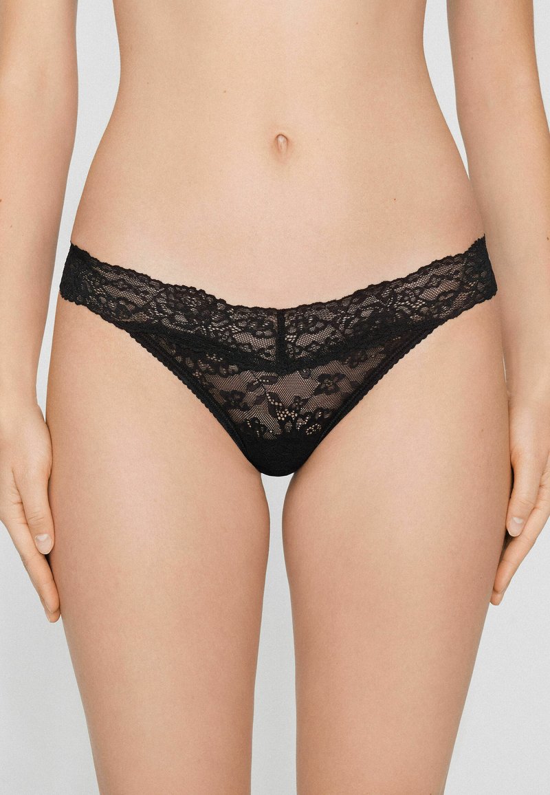 Schwarzer Spitzen-String mit floralem Muster, ausgestattet mit einem breiteren Spitzenbund und zartem Mesh-Gewebe, das durchsichtige Abdeckung und filigrane Details bietet.